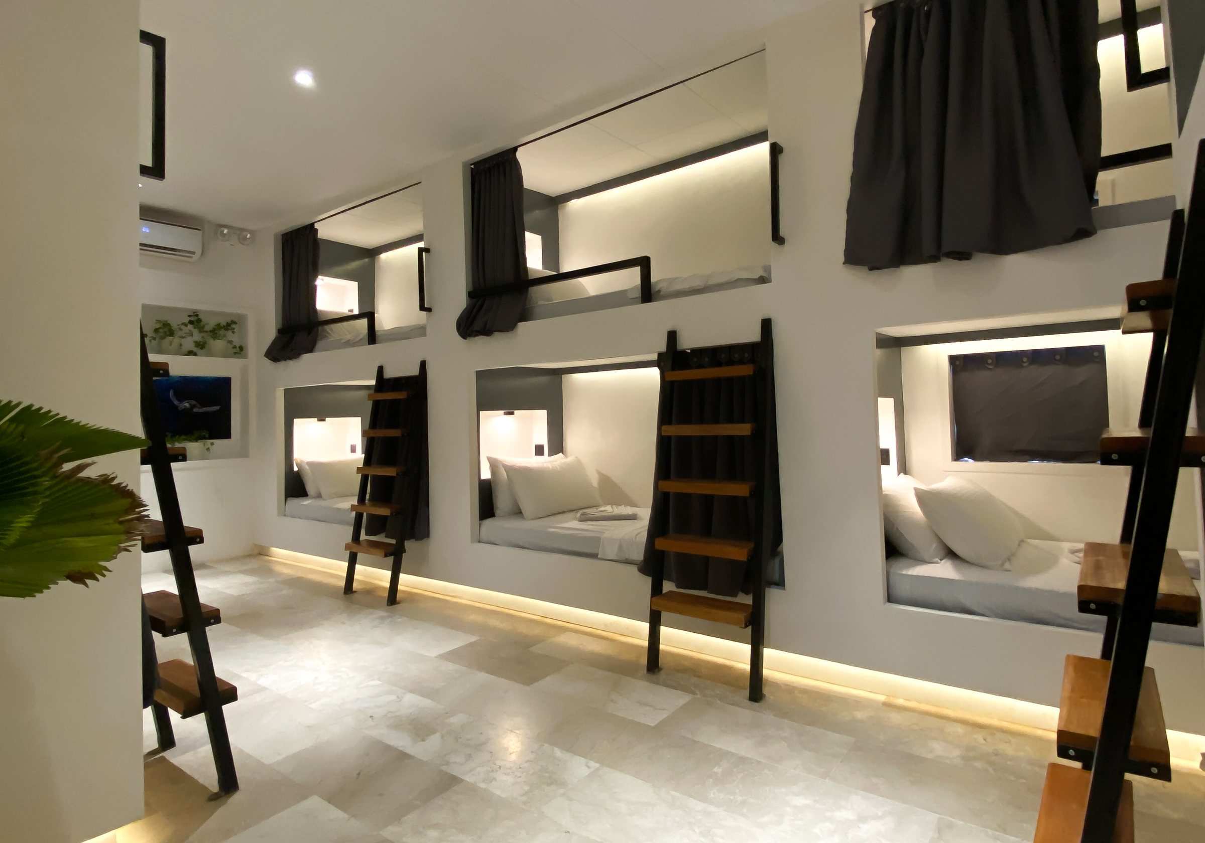 10-bed dorm with lit bunks and privacy curtains