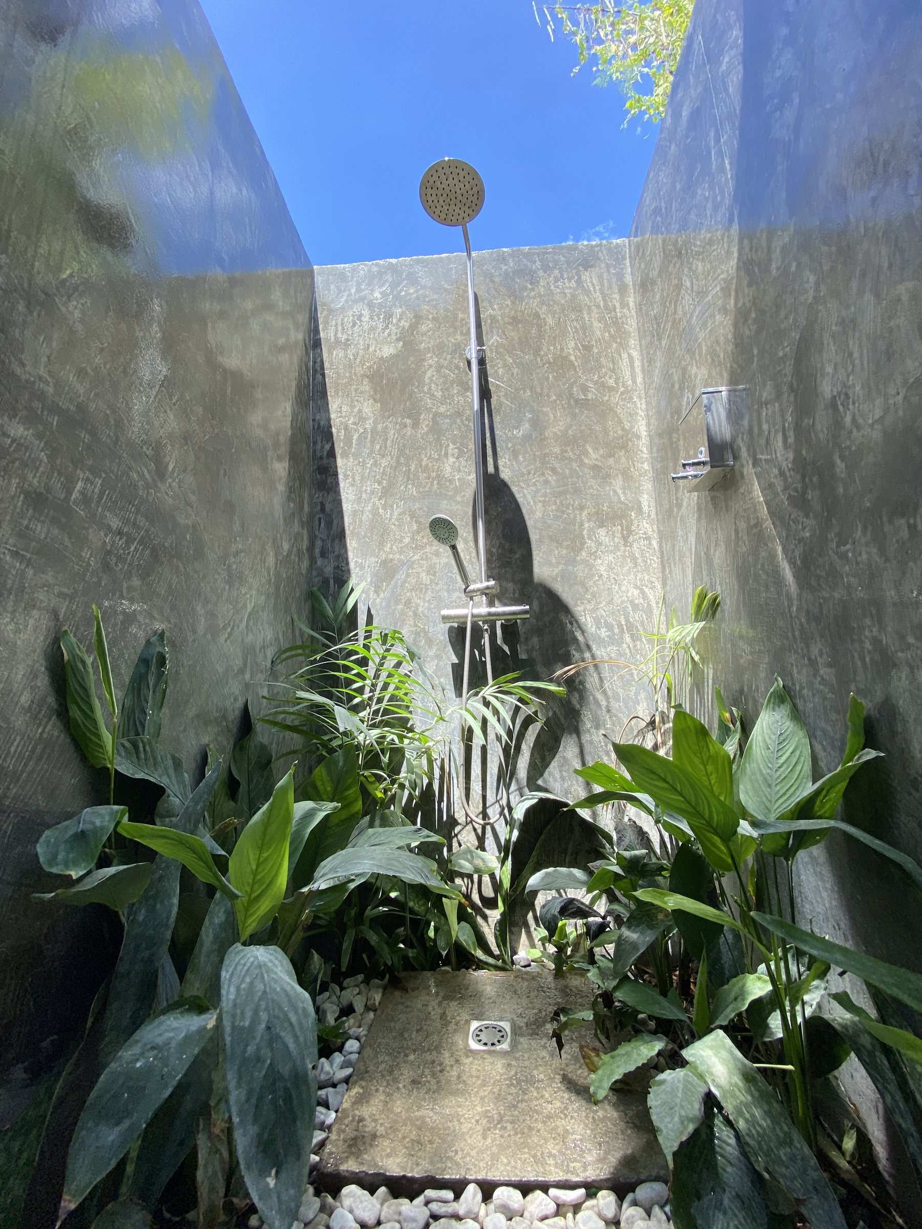 Open-air shower with tropical plants and blue sky